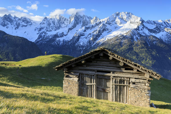 Alpine hut framed by meadows and snowy peaks at dawn Tombal Soglio Bregaglia Valley canton of Graubünden Switzerland Europe