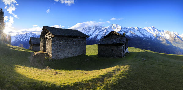 Panorama of huts and valley framed by snowy peaks at dawn Tombal Soglio Bregaglia Valley canton of Graubünden Switzerland Europe