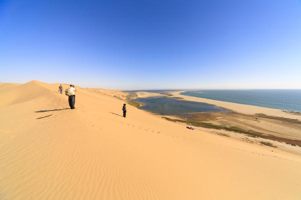 People on sand dunes admires the Atlantic Ocean and lagoons in Walvis Bay Namib Desert Erongo Region Namibia Southern Africa