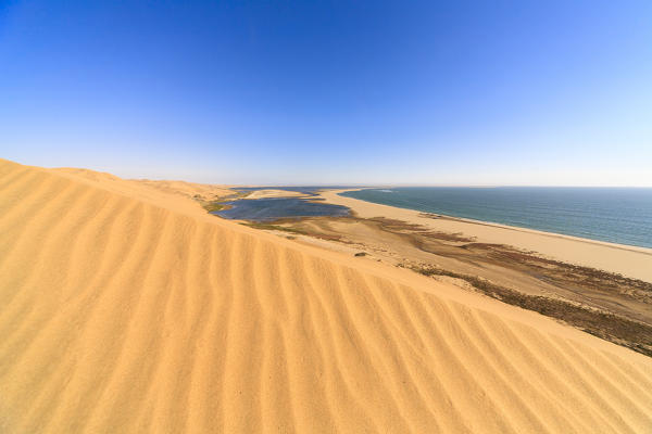 Sand dunes modeled by wind meet the Atlantic Ocean and lagoons in Walvis Bay Namib Desert Erongo Region Namibia Southern Africa