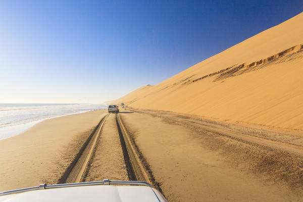 Jeep on the coast between sand dunes and the Atlantic Ocean Walvis Bay Namib Desert Erongo Region Namibia Southern Africa