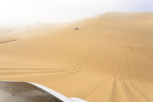Jeep on the sand dunes shrouded by mist Walvis Bay Namib Desert Erongo Region Namibia Southern Africa