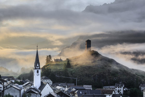 Misty sky on the alpine village of Ardez at sunrise, canton of Graubünden, district of Inn, lower Engadine, Switzerland, Europe