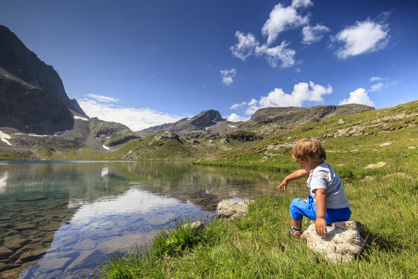 Child on the shore of alpine lake, Leg Grevasalvas, Julierpass, Maloja, canton of Graubünden, Engadine, Switzerland