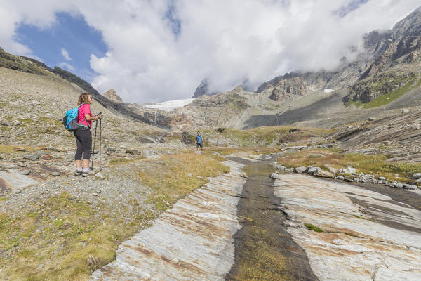 Hikers on path Sentiero Glaciologico with Fellaria Glacier in the background, Malenco Valley, Valtellina, Lombardy, Italy