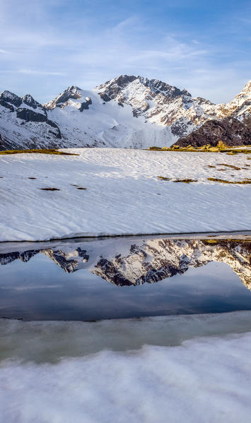 The Disgrazia mount, one of the most beautiful and famous peaks of the Rhaetian Alps, reflecting in the melting water of Lake Scermendone Valtellina, Sondrio, Lombardy, Italy. Europe