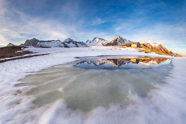 Lake Scermendone during the vernal thaw reflecting Mount Disgrazia  at sunset Valtellina, Sondrio, Lombardy, Italy. Europe