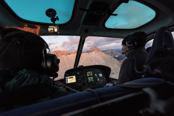 People in the cockpit of helicopter in flight towards Sassopiatto, Dolomites, South Tyrol, Italy