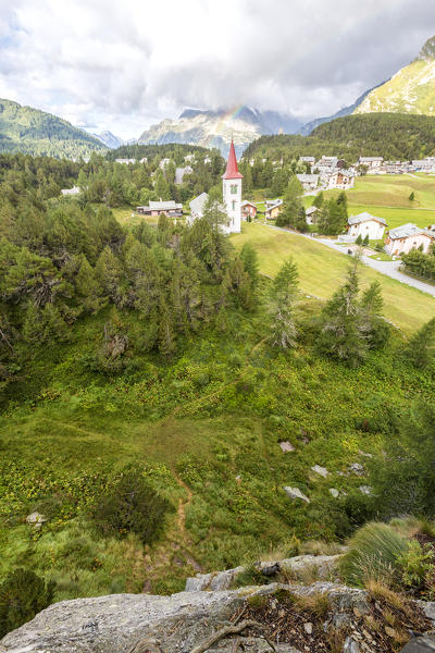 Rainbow over Chiesa Bianca and the village of Maloja, Bregaglia Valley, Canton of Graubunden, Engadin, Switzerland