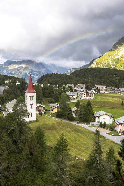 Rainbow over Chiesa Bianca and the village of Maloja, Bregaglia Valley, Canton of Graubunden, Engadin, Switzerland