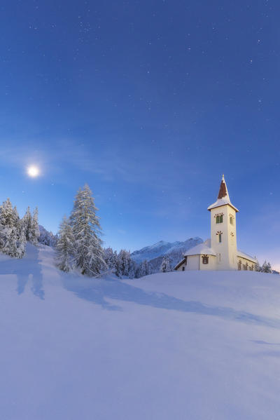 Moon lights up Chiesa Bianca surrounded by snow, Maloja, Bregaglia Valley, Canton of Graubunden, Engadin, Switzerland