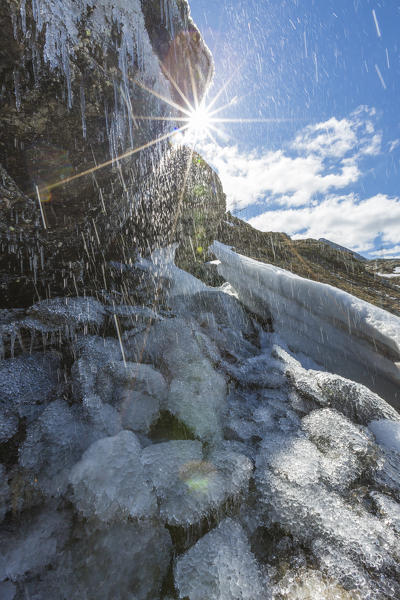 Sunburst on the melting ice on rocks, Bernina Pass, canton of Graubunden, Engadine, Switzerland