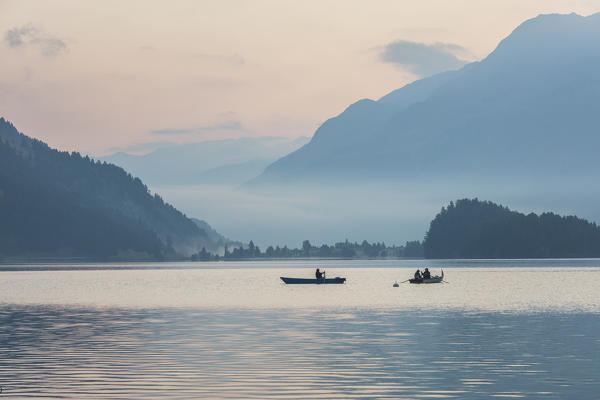 Fishermen in the calm water of Lake Sils at sunrise, Plaun da Lej, canton of Graubunden, Engadine. Switzerland