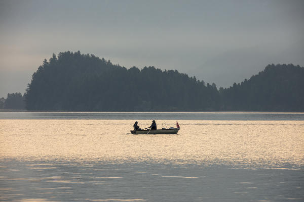 Fishermen in the calm water of Lake Sils at sunrise, Plaun da Lej, canton of Graubunden, Engadine. Switzerland