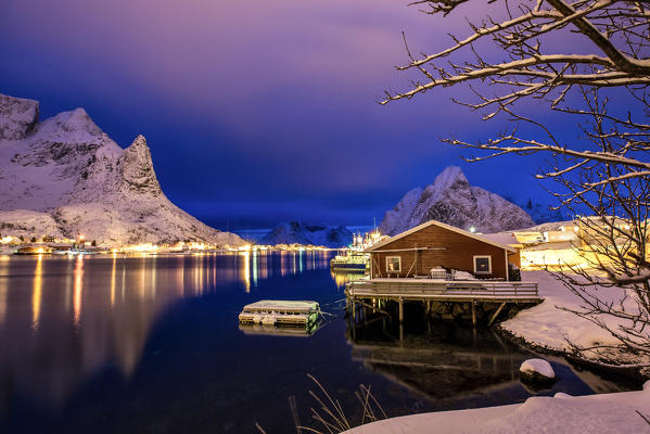 A rorbu, the typical Norwegian fishermen house, reflecting in the still water of the sea at the blue hour in Reine, Lofoten islands, Norway. Europe