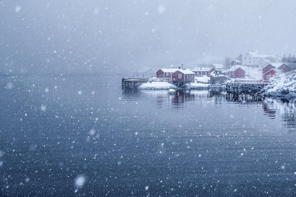 Heavy snowfall on the fishing village and the icy sea Nusfjord Lofoten Islands Norway Europe