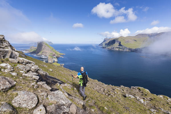 Hiker on cliffs overlooking  Drangarnir rock, Vagar Island, Faroe Island