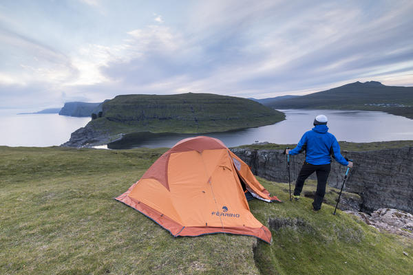 Camping tent and hiker on cliff above lake Sorvagsvatn, Vagar Island, Faroe Islands