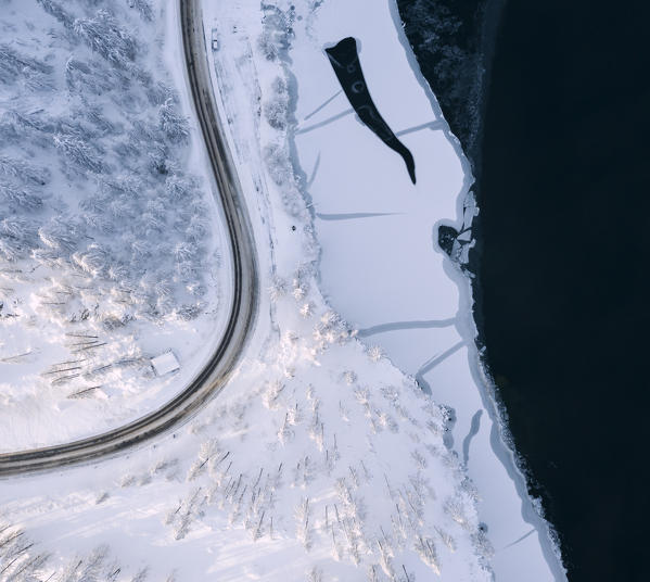 Aerial panoramic view of road around frozen Lake Sils, Plaun da Lej, Maloja Region, Canton of Graubunden, Engadin, Switzerland