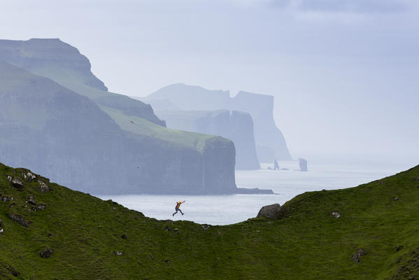 Man jumping on cliffs, Kalsoy island, Faroe Islands, Denmark