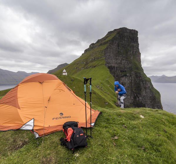 Hiker and tent on cliffs around Kallur Lighthouse, Kalsoy island, Faroe Islands, Denmark