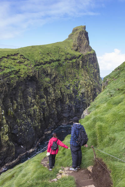 Hikers on steep path on cliffs, Mykines island, Faroe Islands, Denmark