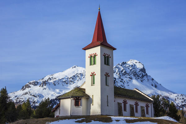 The church tower frames the snowy peaks on a spring day Maloja Pass Canton of Graubunden Switzerland 