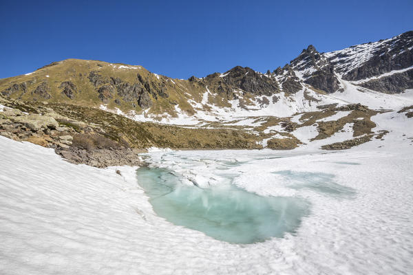 The spring thaw reveals the turquoise water of Laj dal Teo Poschiavo Valley Canton of Graubunden Switzerland 