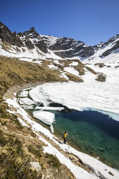 Photographer at Laj dal Teo where snow begins to melt due to spring thaw Poschiavo Valley Canton of Graubunden Switzerland 
