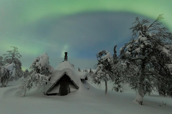 Northern lights on wood hut covered with snow, Pallas-Yllastunturi National Park, Muonio, Lapland, Finland