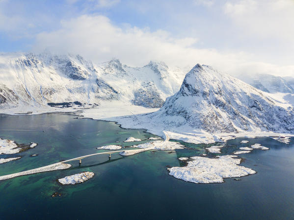 Aerial panoramic view of snowy peak of Volanstinden and Fredvang bridge, Lofoten Islands, Norway