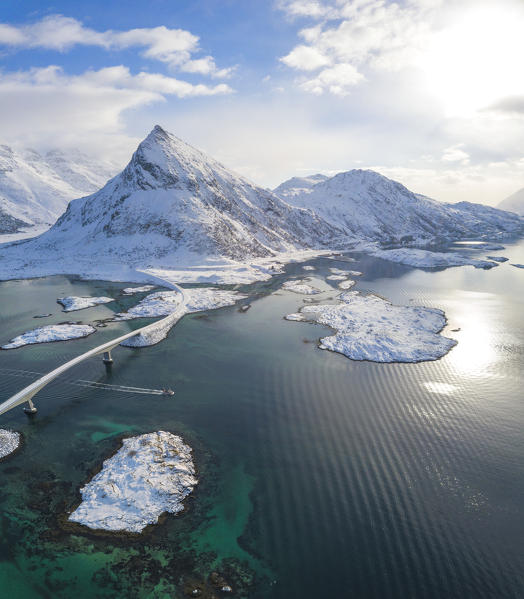 Aerial panoramic view of snowy peak of Volanstinden and Fredvang bridge, Lofoten Islands, Norway