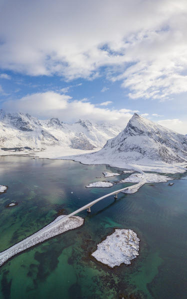 Aerial panoramic view of snowy peak of Volanstinden and Fredvang bridge, Lofoten Islands, Norway