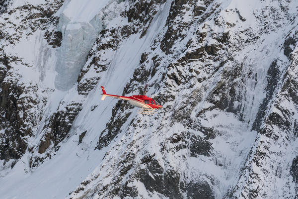 Helicopter in flight beside the north face of Monte Disgrazia, Valmalenco, Val Masino, Valtellina, Lombardy, province of Sondrio, Italy