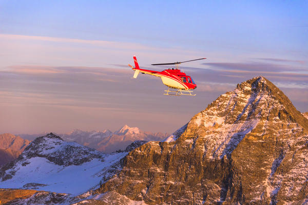 Aerial view of helicopter in flight towards Pizzo Scalino at sunset, Valmalenco, Valtellina, Lombardy, Italy