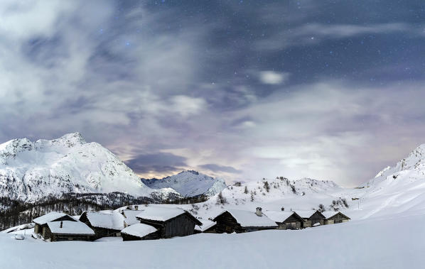 The snow covered roofs of houses of Grevasalvas village under an incredible starry sky. Canton of Graubuenden. Engadine. Switzerland. Europe