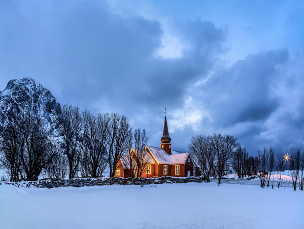Panoramic view of the illuminated church at dusk in the cold snowy landscape at Flakstad Lofoten Norway Europe