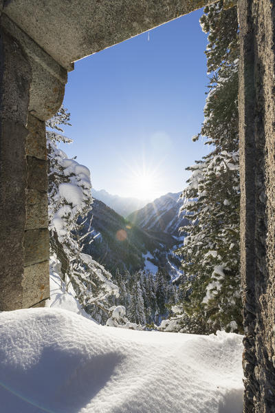 Bregaglia Valley seen from open stone arch surrounded by snow, Maloja Pass, canton of Graubunden, Engadin, Switzerland