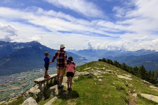Father and sons on top of Alpe Bassetta admire Lake Como, Lower Valtellina, Sondrio province, Lombardy, Italy