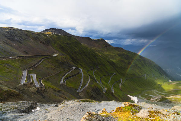 Rainbow on hairpin bends of winding road at Stelvio Pass, South Tyrol side, Valtellina, Lombardy, Italy
