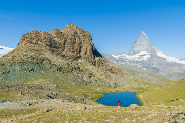 Hiker looks towards Matterhorn from lake Riffelsee, Zermatt, canton of Valais, Switzerland