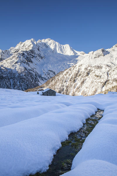 Creek surrounded by snow with Monte Vazzeda on background, Alpe dell'Oro, Valmalenco, Valtellina, Lombardy, Italy