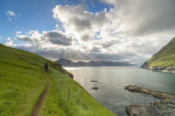 Hiker on grass hill oceanfront, Gjogv, Eysturoy island, Faroe Islands, Denmark (MR)