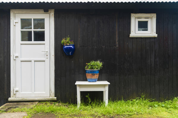 White door and flowerpots on wooden facade of traditional house, Mykines island, Faroe Islands, Denmark