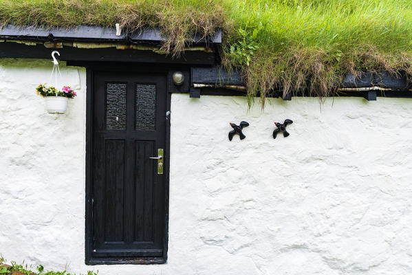 Flowerpot and ornaments on facade of iconic house with grass roof, Mykines island, Faroe Islands, Denmark