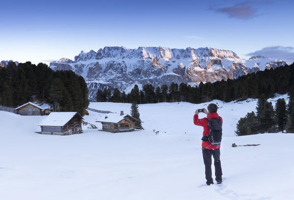 A hiker is taking a photo of a beautiful sunset in Val Gardena, Bolzano province, South Tyrol, Trentino Alto Adige, Italy