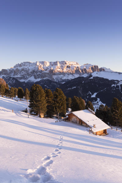 a view of a beautiful winter sunset in Val Gardena with an alpine hut in foreground and the Sella Group in the background, Bolzano province, south Tyrol, Trentino Alto Adige, Italy
