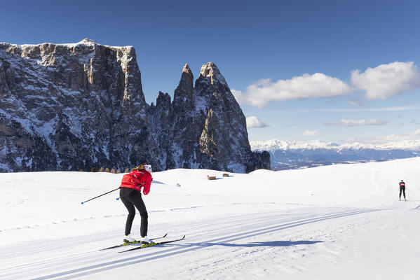 two athletes are running with cross-country skis on Seiser Alm with the Schlern in the background, Bolzano province, South Tyrol, Trentino Alto Adige, Italy