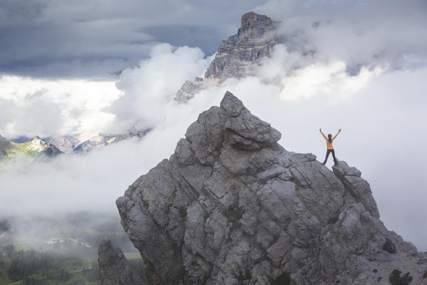 a climber stands on a peak looking at the Mount Pelmo going out of the clouds, Belluno province, Veneto, Italy
