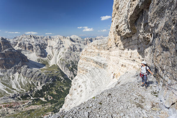 a climber along the via ferrata Lipella on the Tofana di Rozes is looking at the landscape around her, Belluno province, Veneto, Italy